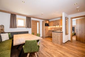 een keuken en woonkamer met een houten tafel en stoelen bij BEIM LOIS Edelweiss - AlpenLuxus Collection in Gerlos