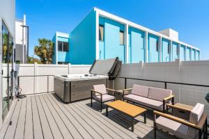 ココアビーチにあるSalty Serenity Villa - New Luxe Escape with Hot Tub Spa & Rocket Views - Walk to Beachの建物の上にホットタブと椅子が置かれたデッキ