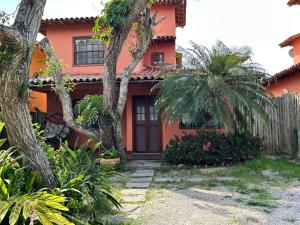 a red house with palm trees in front of it at Casa Quinta do Atlântico - Aconchego da Paz 150m da praia in Búzios