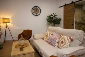 a living room with a couch and a clock on the wall at Apartamento Esencia en la Roca in Setenil