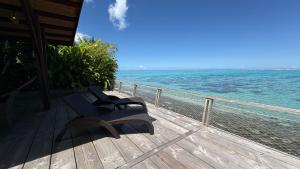 a bench sitting on a deck looking at the ocean at Villa Miti Vai by ENJOY VILLAS in Iumaru