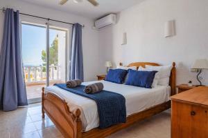 sypialnia z łóżkiem z niebieskimi poduszkami i oknem w obiekcie Villa Moggalatto by Villa Plus w mieście Calpe