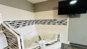 a bathroom with a tub and a tv on the wall at Catalina Airport Motel in Sterling Heights +26 photos