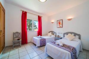 a room with two beds and a window with red curtains at Villa Verde by Villa Plus in Balcon del Mar +12 photos