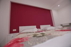 a bedroom with a bed with a red wall at Villa Flowers in Međugorje