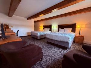 里弗顿Tomahawk Motor Lodge By OYO Riverton US-26的有两张床和一把椅子的酒店房间