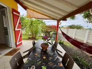a table with chairs and a hammock on a patio at Résidence les Orchidées in Les Trois-Îlets
