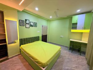 a bedroom with a yellow bed and a desk at Alpine Nest in Dibrugarh +3 photos