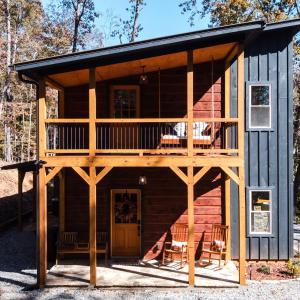 a log cabin with a balcony and a deck at Modern Luxe Cabin! River Fun, Deer, Pool & Firepit in Ellijay