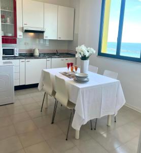 a white kitchen with a table with plates and wine glasses at Apartment Sunrise Pesaro in Pesaro