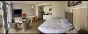 a bedroom with a bed and a table and a kitchen at Studio Chateliers, piscine chauffée, spa et jardin à St Martin de Ré in Saint-Martin-de-Ré