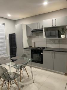 a kitchen with a glass table and chairs in it at WeThusiCBD in Mbabane