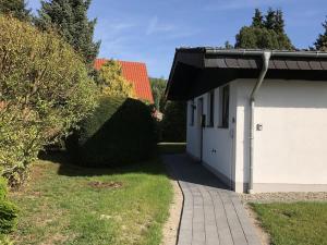 a white building with a garage and a walkway at Ferienhaus Trüdi 2 - Gemütlicher freistehender Bungalow in Wolfshagen
