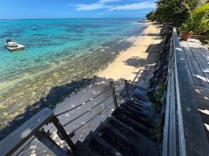 a stairway leading to the beach with a boat in the water at Villa Miti Vai by ENJOY VILLAS in Iumaru