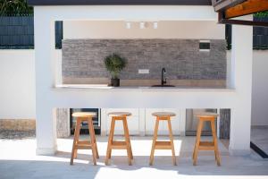 a kitchen with three wooden stools in front of a counter at Vacation villa Matic with 7 bedrooms in Sinj