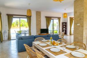 un salon avec un canapé bleu, une table et des chaises dans l'établissement Villa Elissa by Villa Plus, à Pólis Chrysochoús