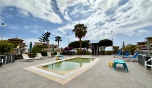 a patio with a swimming pool with chairs and tables at GORGEOUS VIEW Villa & Sauna, Golf Costa Adeje in Adeje