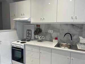 a kitchen with white cabinets and a sink and a stove at Aggelikas apartments 2 in Paleokastritsa