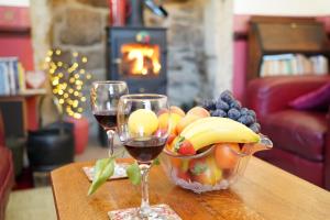 zwei Gläser Wein und eine Schale Obst auf dem Tisch. in der Unterkunft Traditional 2 Bedroom Cottage in Eyam Hope Valley in Eyam