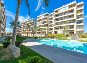 a large apartment building with a swimming pool and palm trees at Elemental - Vista Villa Iii in Cabo San Lucas