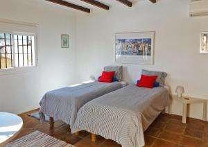 zwei Betten in einem weißen Zimmer mit roten Kissen in der Unterkunft Ferienhaus mit Privatpool für 4 Personen ca 190 m in Sedella, Andalusien Costa del Sol in Sedella
