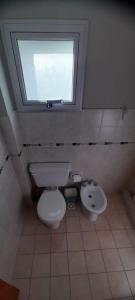a bathroom with a toilet and a sink and a window at la posta in Puerto Pirámides +9 photos