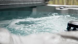 a bath tub filled with water with a black object at The Saige - Hot Tub, Fire Pit, and huge entertainment area in Logan