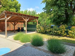 eine hölzerne Pergola in einem Garten mit Gras in der Unterkunft Oliva 8 fős Balatoni Nyaraló in Balatonakarattya