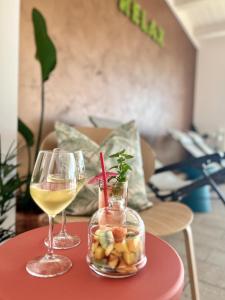 two glasses of wine and a bowl of fruit on a table at Villa Aniana - Hotel, Relax, Spa in Massignano
