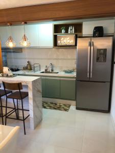 a kitchen with a stainless steel refrigerator and a table at Vista mar sol&mar in Vila Velha