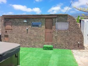 a brick building with two windows and a green lawn at EL Cobijo in Guía de Isora