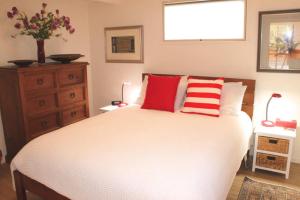 a bedroom with a large bed with red and white pillows at Valhalla North & Northern Lodge - waterfront, rural, semi-isolated in Kerikeri