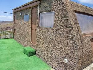 a brick house with a green lawn in front of it at EL Cobijo in Guía de Isora