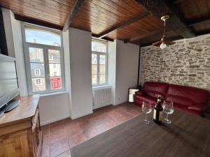 un soggiorno con un divano rosso e due bicchieri di vino di Le cottage des remparts Le triplex a Boulogne-sur-Mer