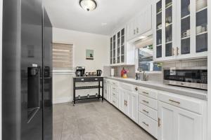 a kitchen with white cabinets and a stainless steel refrigerator at Timeless Charm by the Coast, Vintage Beach Bungalow in Long Beach