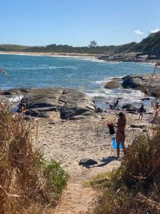 a young girl standing on a beach near the water at Via sol casa 2 térreo in Rio das Ostras