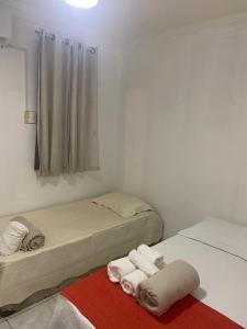 a room with two beds and towels on a red rug at COP 30 - Imóvel Próximo ao Aeroporto e ao Hangar - 02 in Belém