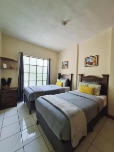 a hotel room with two beds and a window at Mazaryk Bed and Breakfast in Antigua Guatemala +19 photos