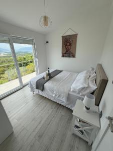 a white bedroom with a bed and a large window at Sisters residence in Kotor