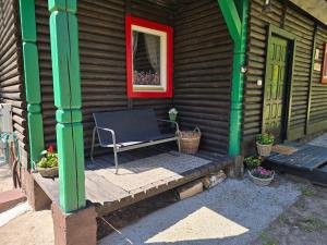 una panchina seduta sul portico di una baita di tronchi di Na Zboczu - Rodzinny Domek w Lesie na Mazurach z Basenem i Sauną a Guzowy Piec