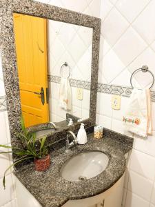 a bathroom sink with a yellow door and a mirror at Casa Rústica da Rua do Carmo - Diamantina - MG in Diamantina
