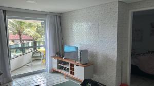 ein Wohnzimmer mit einem TV und einem Balkon in der Unterkunft Resort Ancorar Porto de Galinhas Flat 1202 in Porto De Galinhas + 52 Fotos
