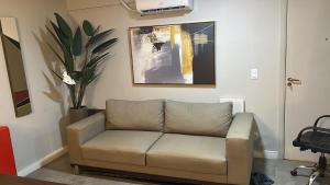 een bank in een woonkamer met een schilderij aan de muur bij Lago sul - Daher in Brasilia
