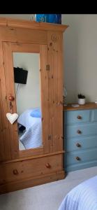 a wooden cabinet with a mirror in a bedroom at Lynne's Place in Carmarthen