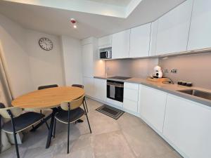 a kitchen with a wooden table and a clock on the wall at Brand New 1BR Pool & Jacuzzi On Site Parking Suite One in Gibraltar