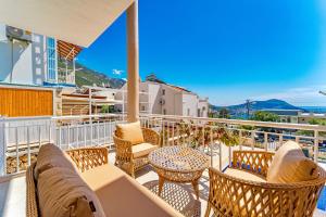 a balcony with chairs and tables and a view of the ocean at Stunning Modern Duplex Apartment in Central Kalkan in Kas