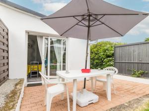 - une table et des chaises blanches avec un parasol sur la terrasse dans l'établissement Gîte indépendant avec terrasse - Proche de St Nazaire et La Baule, au cœur du Parc de Brière - FR-1-306-862, à Saint-Malo-de-Guersac