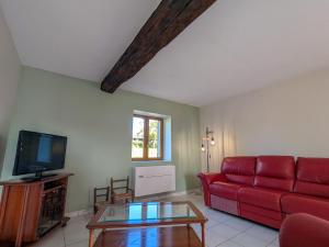 a living room with a red couch and a tv at Gîte à la ferme avec jardin privé, clim et visite de l'exploitation près d'Argenton-sur-Creuse - FR-1-591-321 in Cluis
