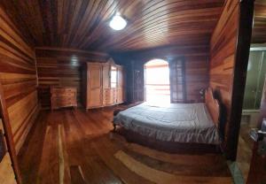 a bedroom with a bed in a wooden room at Recanto Gu&Gui in Camanducaia