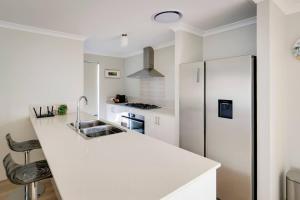 a white kitchen with a sink and a refrigerator at Stables Lane Retreat in Busselton